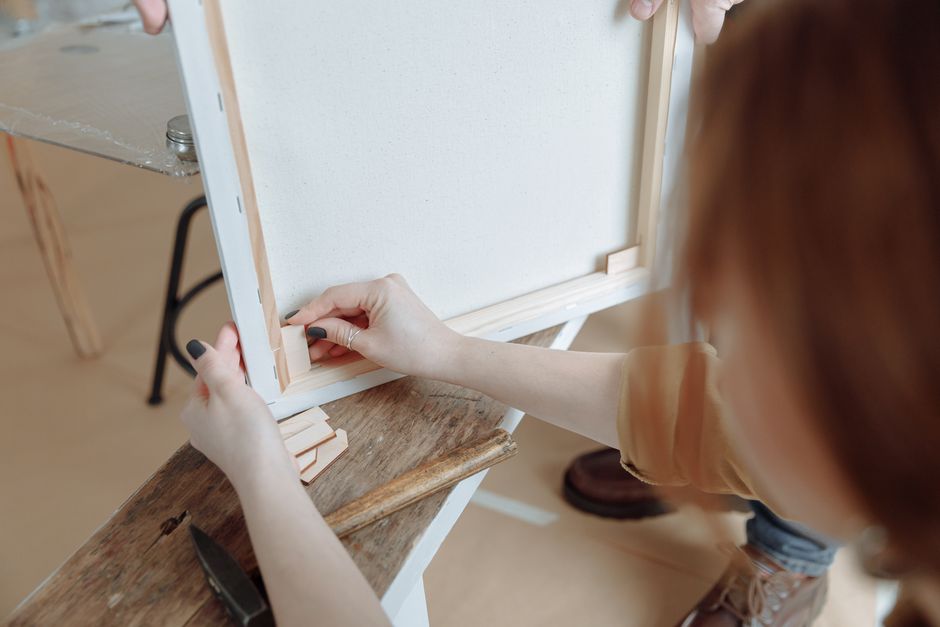Een persoon reinigt een canvas met spons.